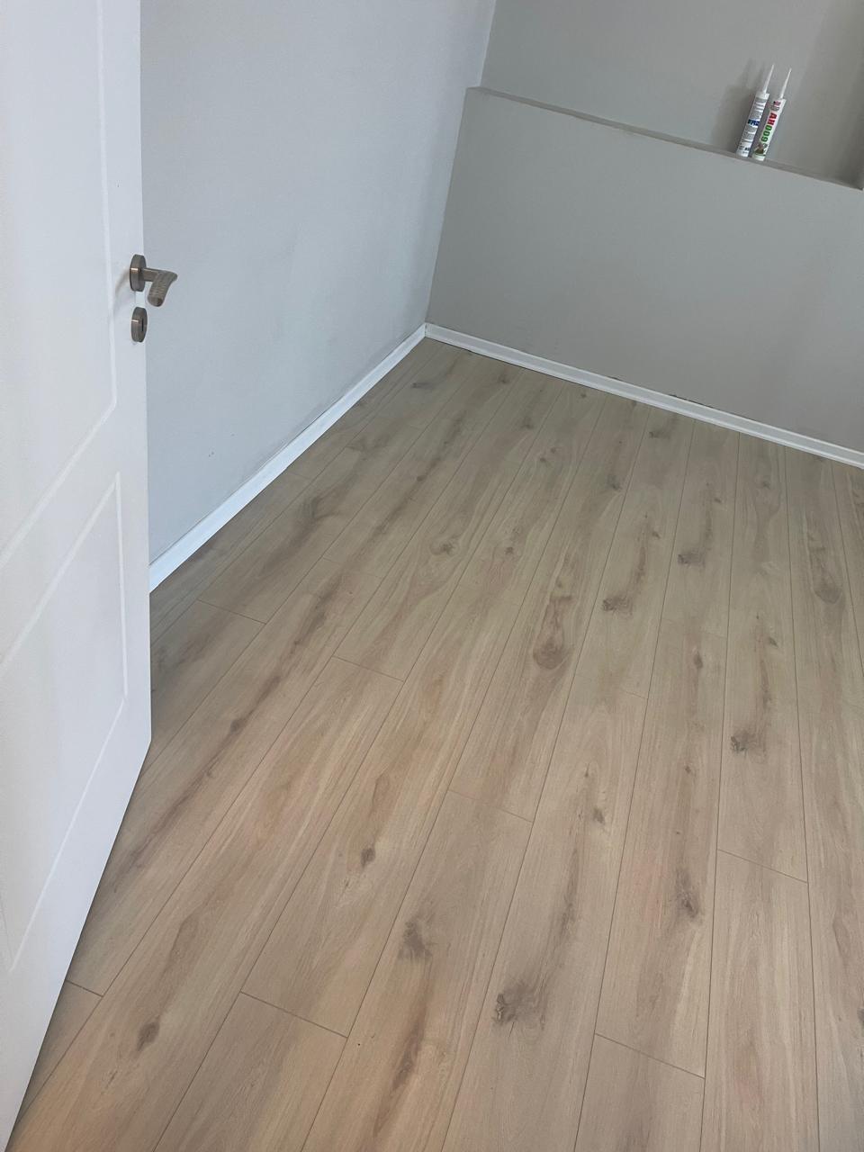 Laminat lisi i lehtë në dhomë me suvatim të bardhë