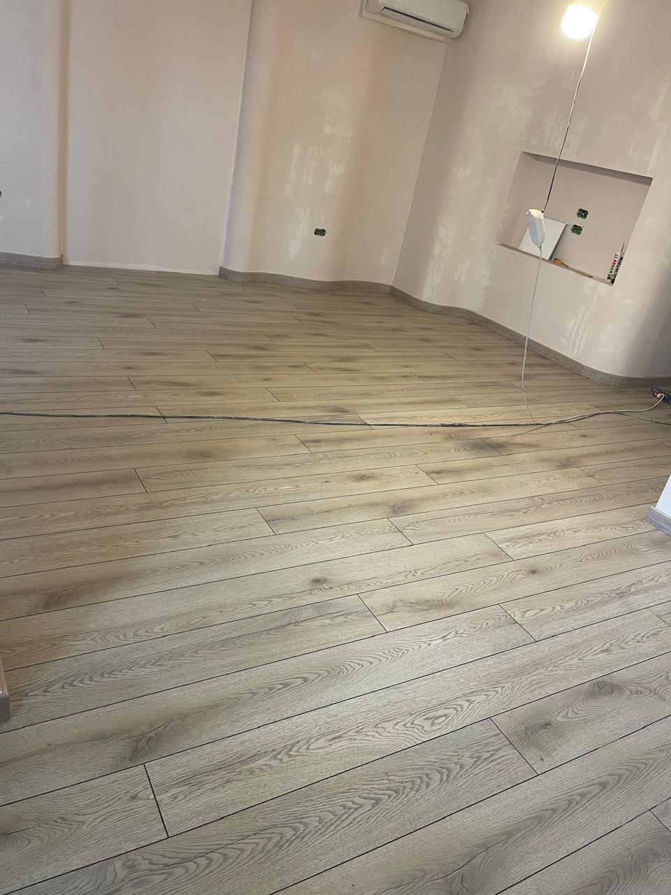 Laminat lisi gri në dhomë të madhe gjatë rinovimit