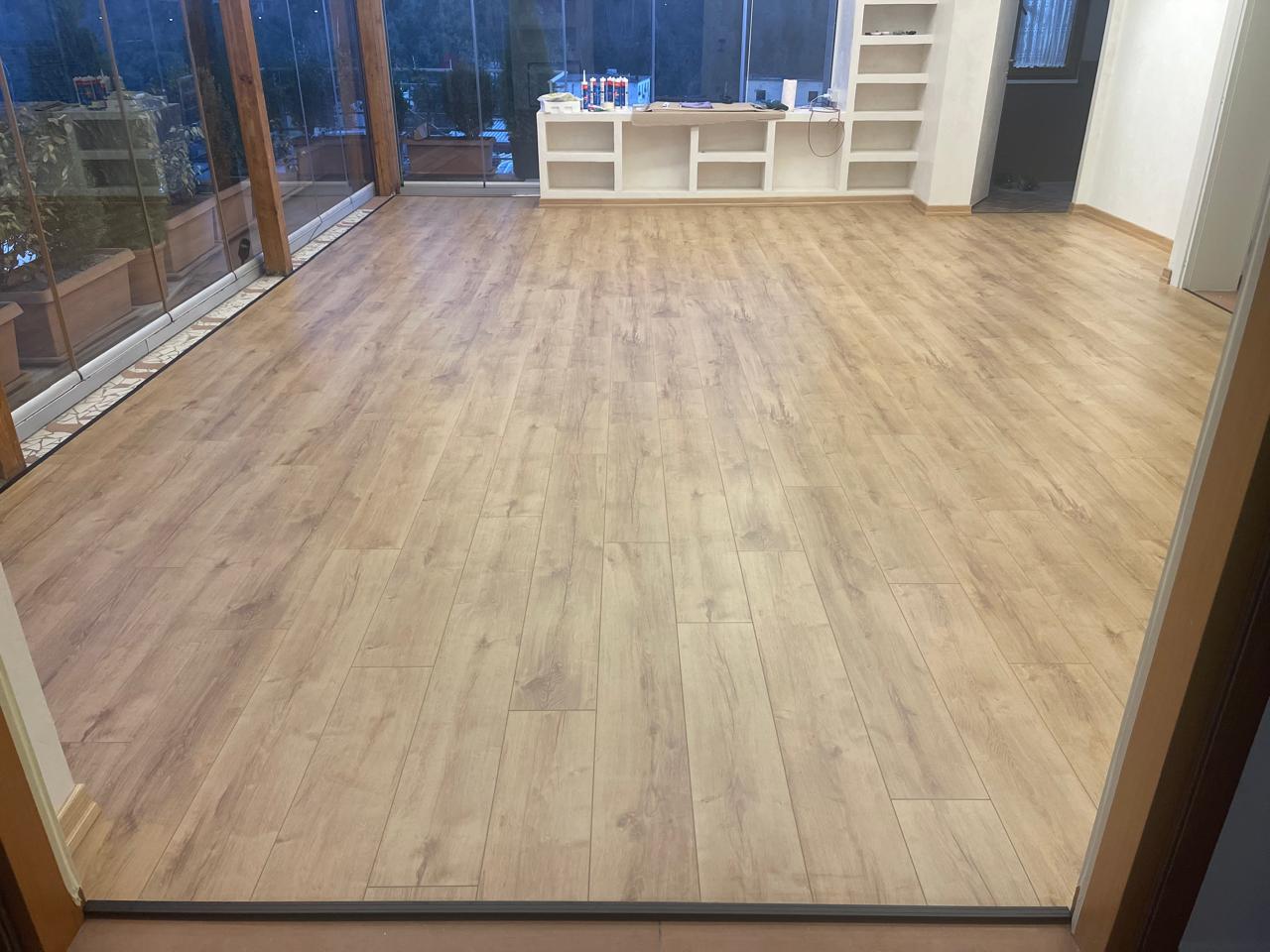 Laminat lisi i lehtë në sallon të gjerë me rafte